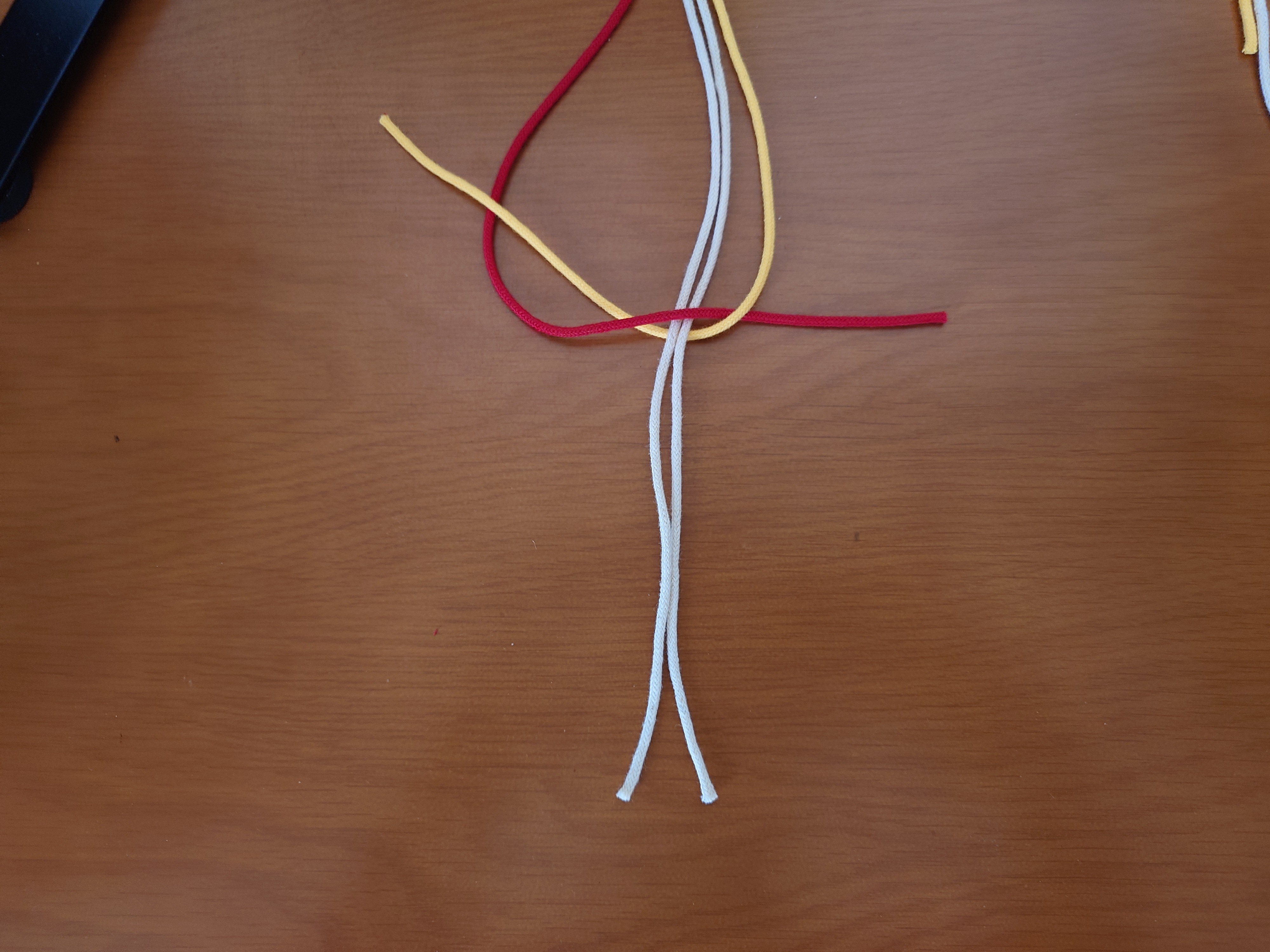 右端の紐を、その他の全ての紐の裏側から通して、三角の中から出す