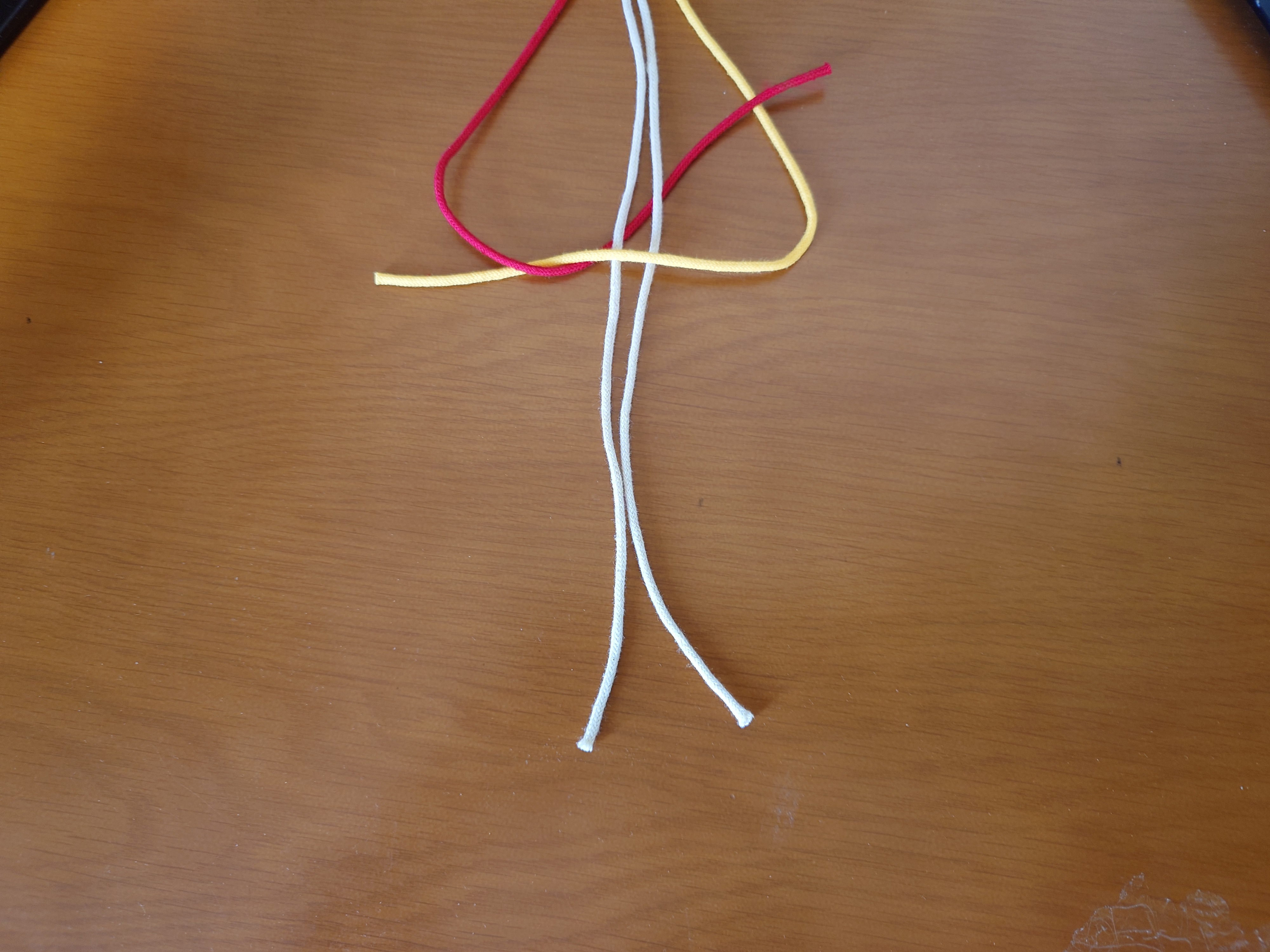 左端の紐を、その他の全ての紐の裏側から通して、三角の中から出す